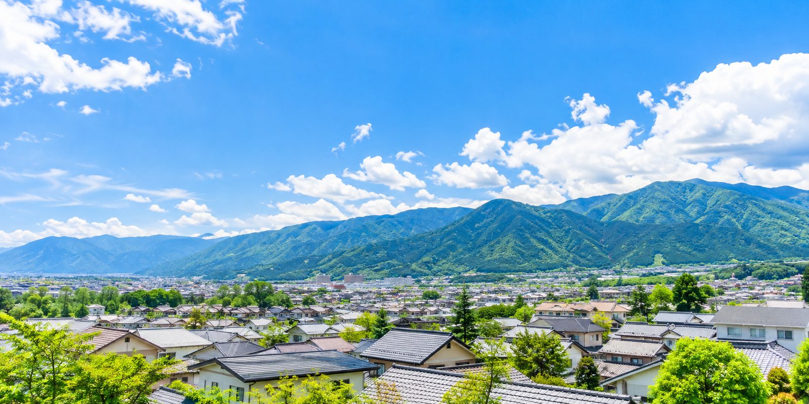 晴れた日の長野の住宅街と、奥に広がる緑の山並み